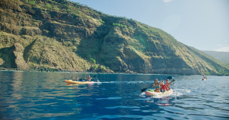 Three tandem kayaks with families paddling across Kealakekua Bay
