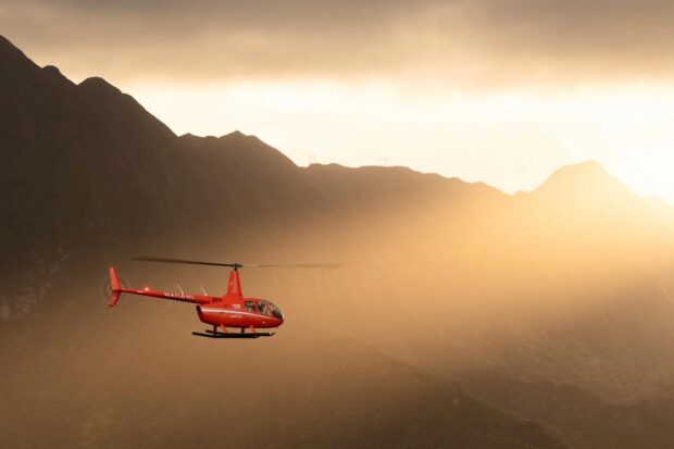 helicopter flying over the ocean during sunset