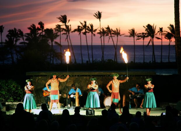 Polynesian performers on stage against a pink sunset sky at the Sunset Luau, Waikoloa Beach Marriott, Big Island