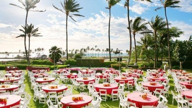 Round tables set for guests on the oceanfront lawn at the Sunset Luau, Waikoloa Beach Marriott