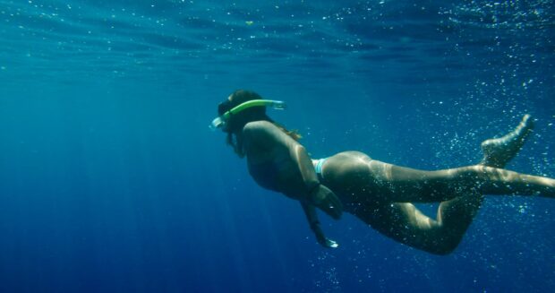A snorkeler underwater in the clear water of Kealakekua Bay