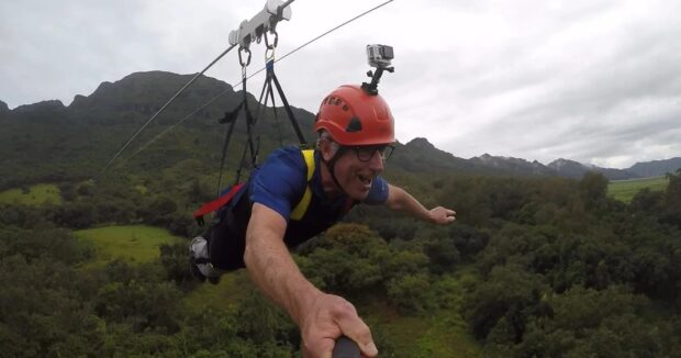 Man soaring in superman pose on the Powerline zipline at Nui Kauai