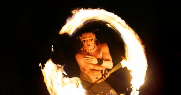 Fire-knife dancer spinning a ring of flame at night at the Grand Wailea luau