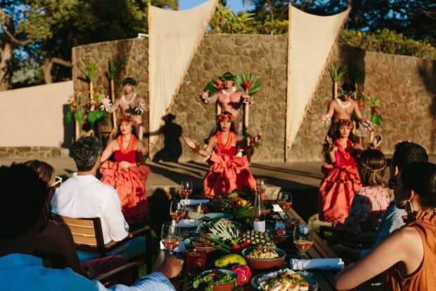 Guests at a table of family-style dishes watching hula dancers at the Grand Wailea luau