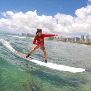woman standing on longboard for first time at waikiki, oahu, hawaii