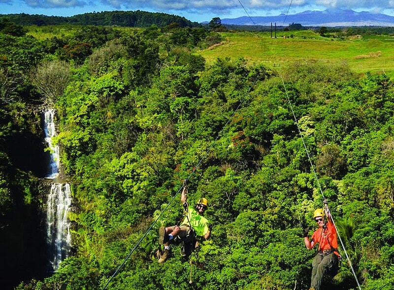 Two riders side by side on dual racing ziplines at Botanical World Adventures, Big Island