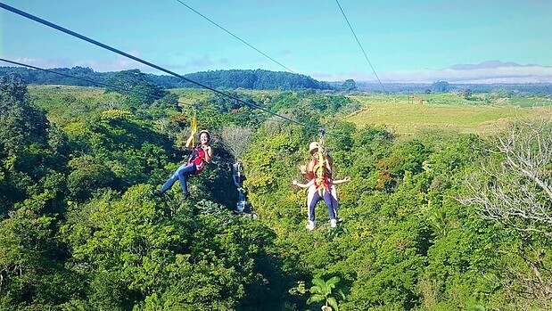 Young child riding tandem with guide on Botanical World Adventures zipline, Big Island