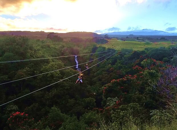 Two riders side by side on dual racing ziplines at Botanical World Adventures, Big Island
