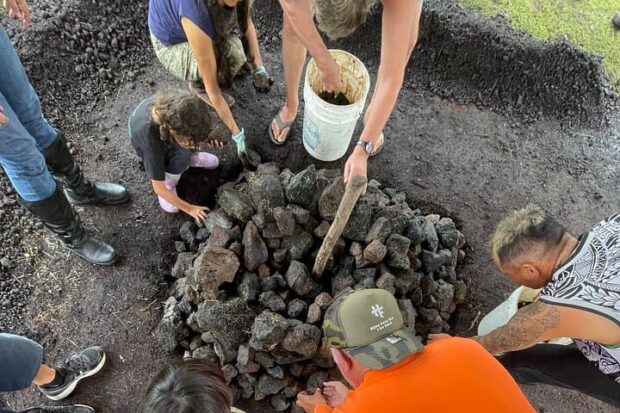 Guests stacking lava rocks into the pit while building an imu at the Imu Mea ʻAi food tour near Pāhoa