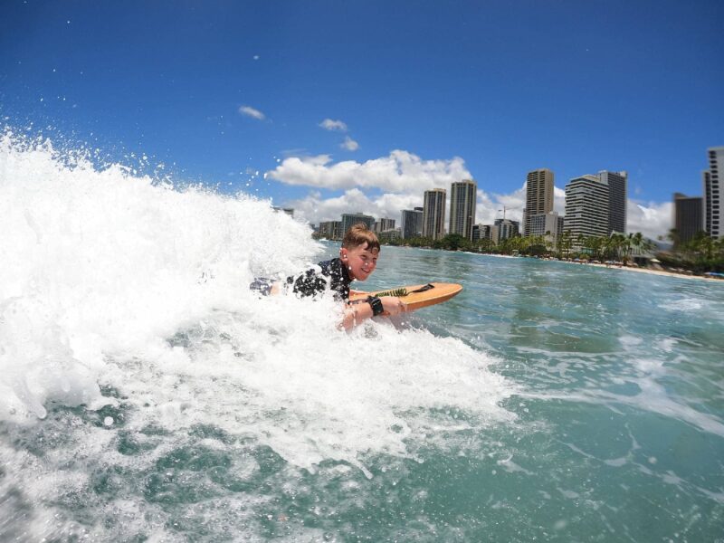 small boy riding a wave at waikiki, hawaii