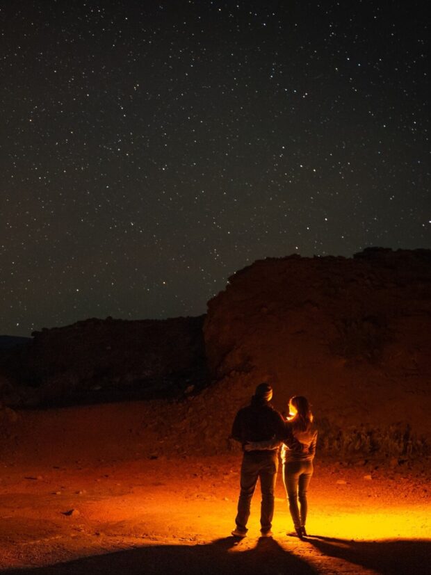 Backlit portrait of a couple with the night sky behind them on the stargazing tour