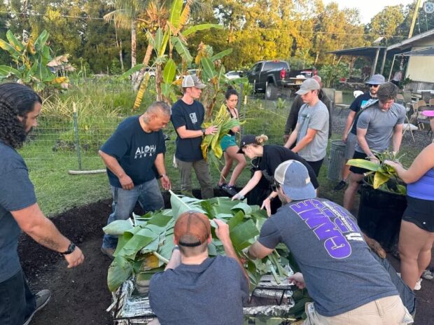 Group covering the imu with banana and ti leaves during the Imu Mea ʻAi food tour