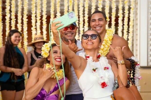 Guests wearing fresh lei take a selfie with a performer at the Na Lei Aloha luau entrance