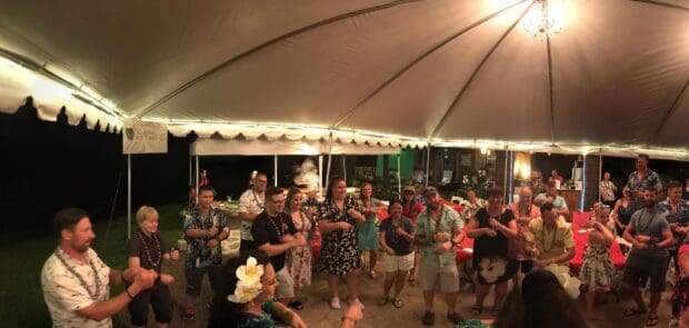 A tent full of guests in kukui lei follows a hula lesson at the Experience Nutridge luau