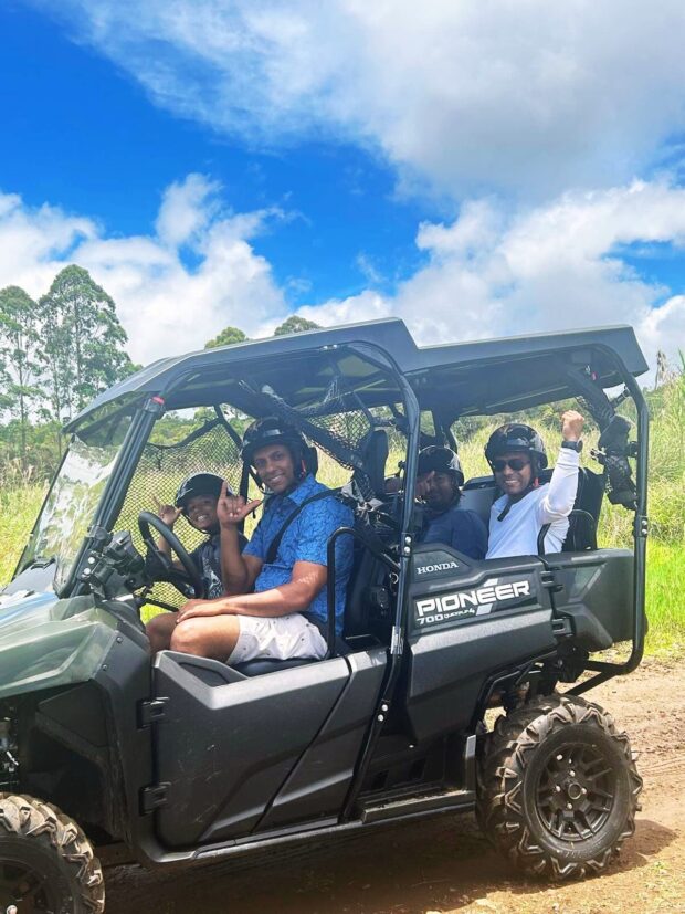 Family of four including a young child riding together in a side-by-side UTV on the Ohana Ranch ATV tour, Big Island