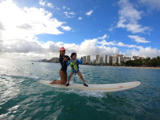 small boy and his mother riding a wave at waikiki, hawaii
