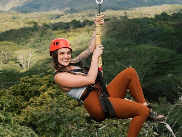 Young girl smiling as she ziplines across a tropical valley on the Kauai Backcountry zipline tour