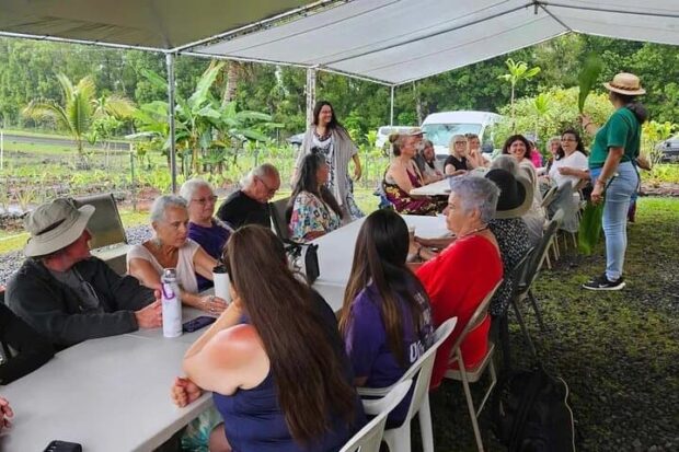Guests seated at long tables under a tent while a host talks story at the Imu Mea ʻAi food tour