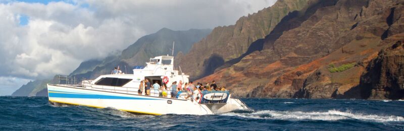 a powerful, sleek, and comfortable, 65-foot power catamaran in front of the napali coast, Kauai