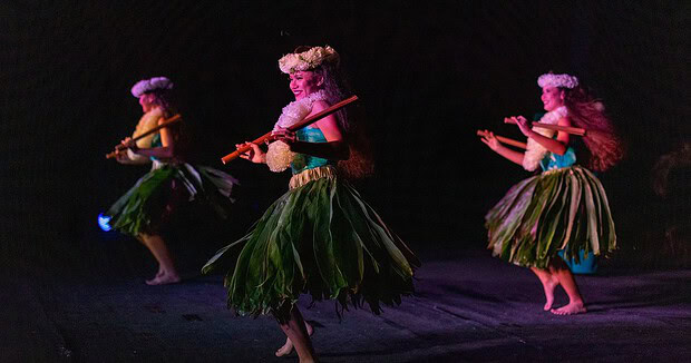 Three hula dancers mid-performance on stage