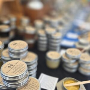 Close-up of Bee Boys rose lavender balm tins at the Keauhou Farmers Market