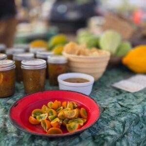 Red plate of cut calamansi samples beside jars of homemade jam at the Keauhou Farmers Market