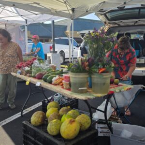 Stand with cut flower bouquets, breadfruit, radishes, and avocados at the Keauhou Farmers Market