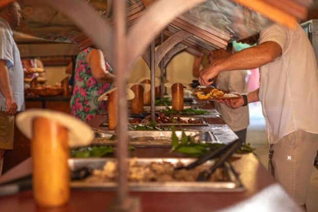 Guests serve themselves from chafing dishes at the Luau Kalamaku buffet under the pavilion