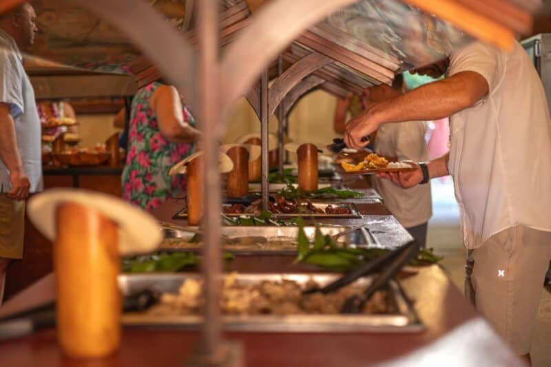 Guests serve themselves from chafing dishes at the Luau Kalamaku buffet under the pavilion