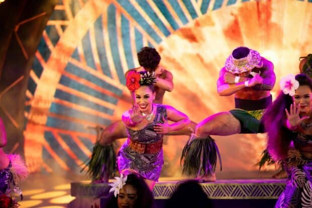 Dancer in a purple tapa-print dress with a red hibiscus leads a group number at the Kaula Luau in Ko Olina