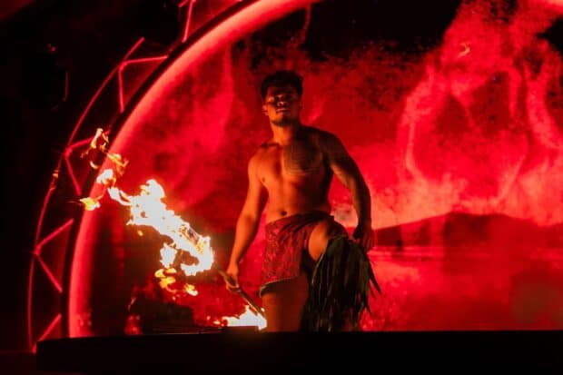 Fire-knife dancer holding a lit knife on stage at the Kaula Luau in Ko Olina