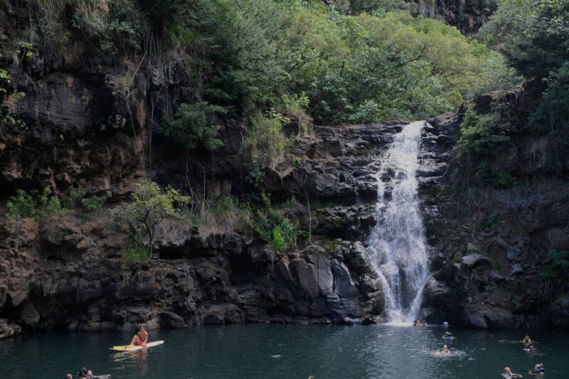 waimea valley waterfalls with people and a kayak in the water