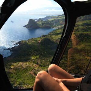 woman sitting in A helicopter crossing the Maui coastline with Haleakala on the horizon