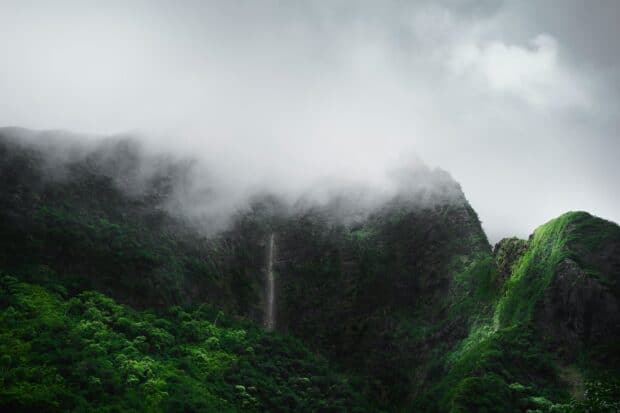 Rain clouds and mist rolling over lush green mountain ridges in Hawaiʻi