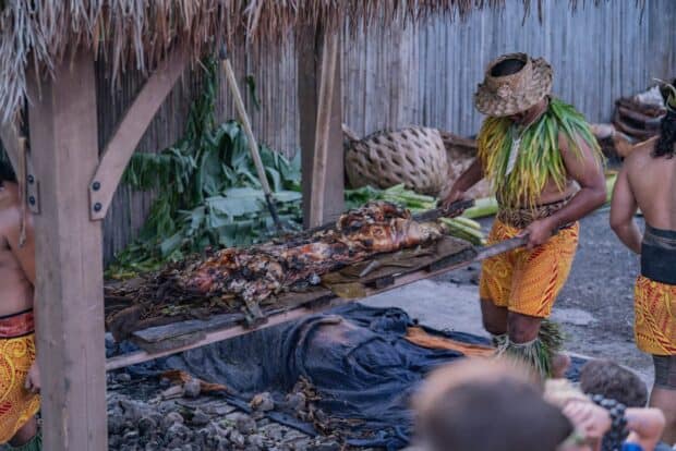 Staff lift a whole roast pig from the imu on a wooden rack at the Mauka Warriors Luau in Kapolei