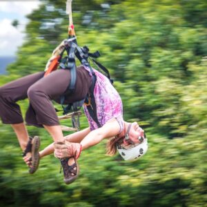 girl hanging upside down on a zipline