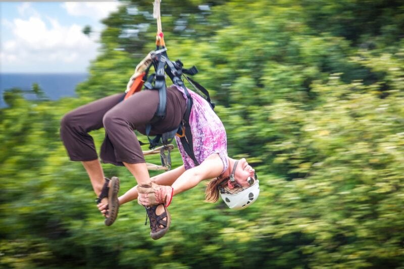 girl hanging upside down on a zipline
