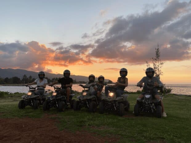 Family on ATVs at sunset by the ocean at North Shore Stables in Waialua, Oʻahu
