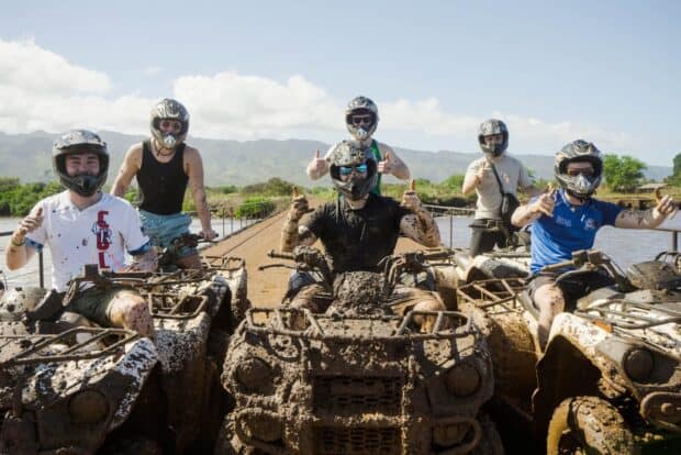 A group of riders on mud-covered ATVs giving thumbs up after the tour at North Shore Stables