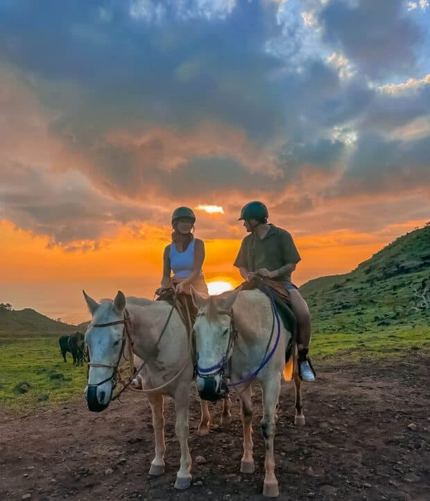 A couple on horseback at sunset on the Pālehua mountain trail, West Oʻahu