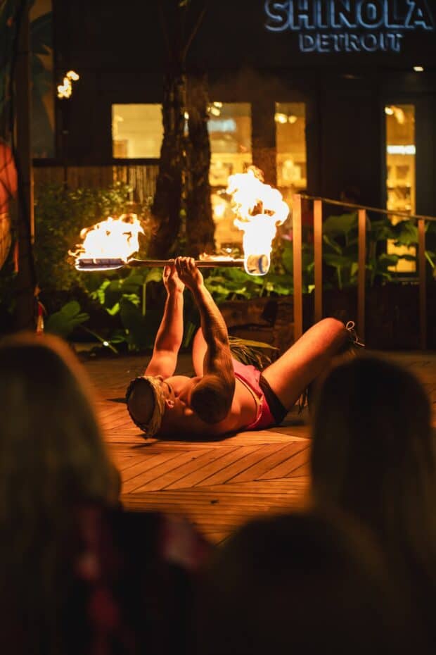 Fire knife dancer on his back spinning a double-lit knife on the deck at Queens Waikiki Luau