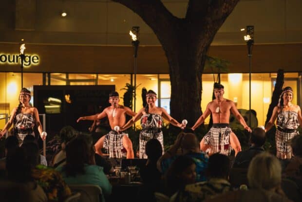 Performers with poi and Māori-style costume in a line on stage at Queens Waikiki Luau