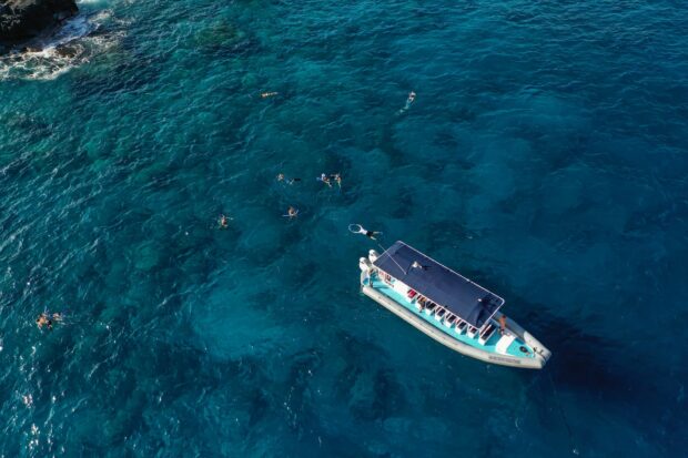 aerial shot of people snorkeling around a boat