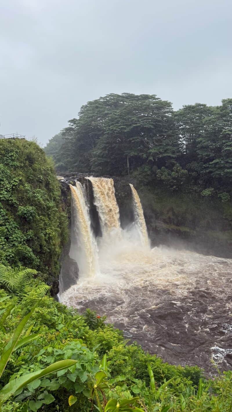 Rainbow Falls in flood, three chutes of brown storm water pouring into the Wailuku River in Hilo