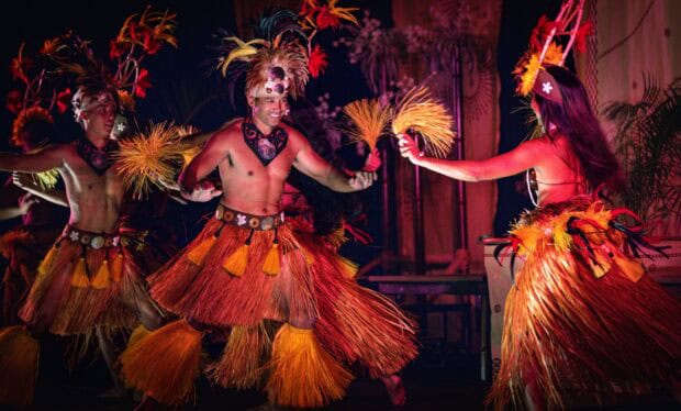 Tahitian dancers in feather headdresses and grass skirts perform at the Tales of the Kapa Moe Lūʻau, Kapalua