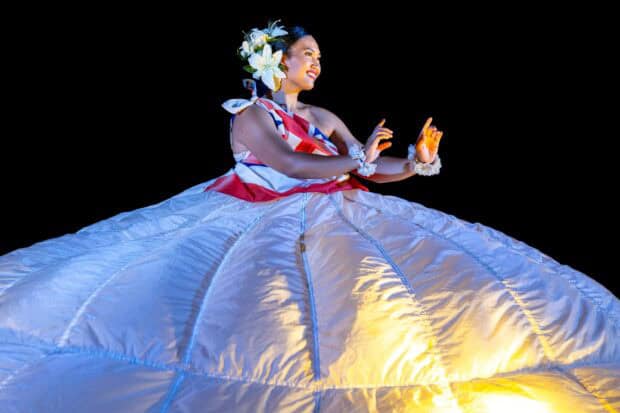 A hula dancer in a lit hoop skirt with a Hawaiian-flag top at the Kapa Moe Lūʻau