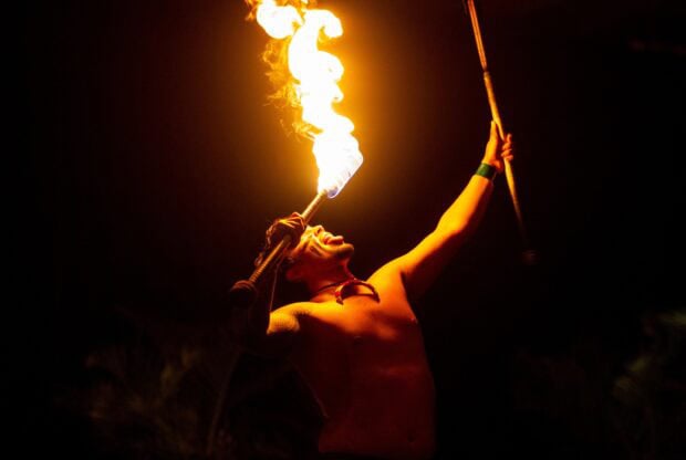 A fire-knife dancer with a lit torch at the Tales of the Kapa Moe Lūʻau