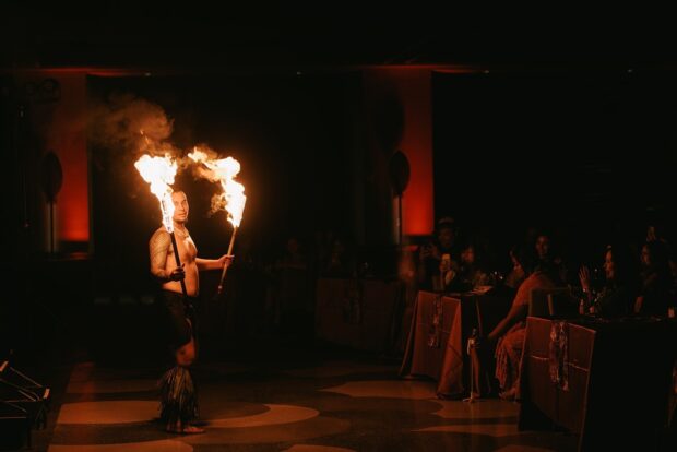 A fire dancer performs beside guest dinner tables inside the Aloha Garden Pavilion