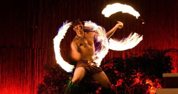 Samoan fire-knife dancer spinning two rings of flame on stage at the Myths of Maui Luau