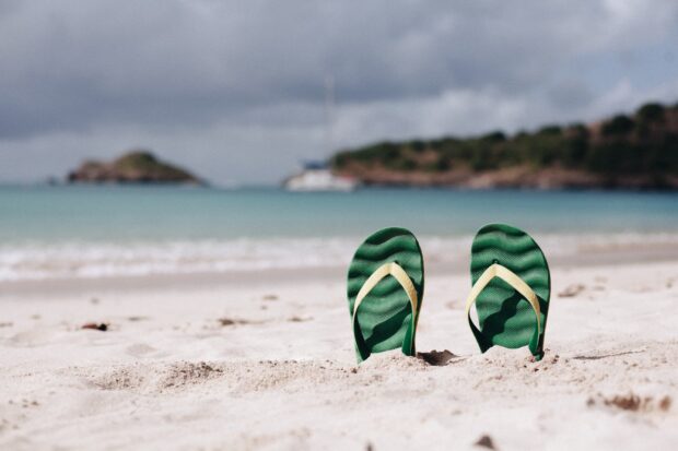 Green flipflops in the white sand at the beach